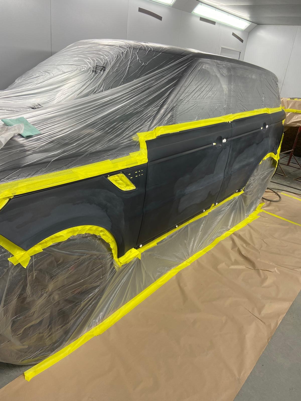 Range Rover Sport rear door and quarter panel masked up in the spray booth, with the bodywork sanded back to bare primer ready for colour