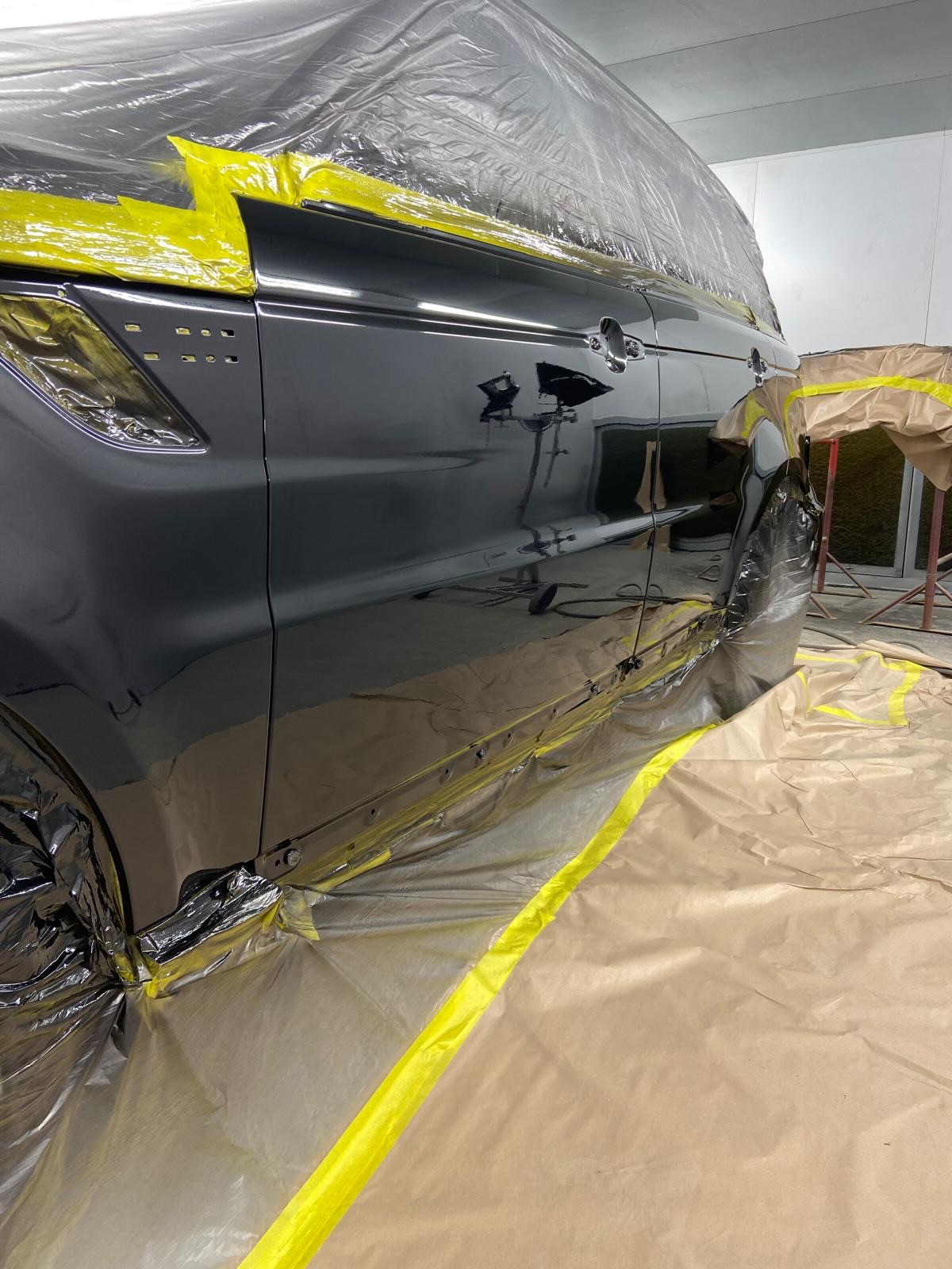 Range Rover Sport door freshly painted in gloss black, with the masking tape being peeled back to reveal the new finish