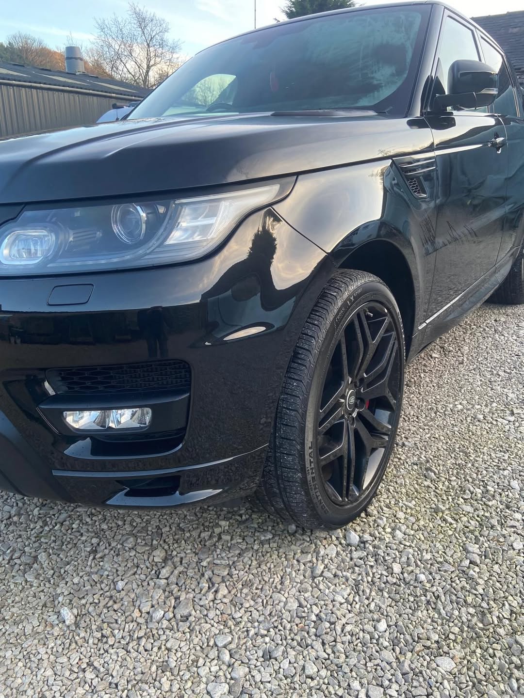 Close-up of the finished Range Rover Sport's front end and wheel, showing the deep gloss finish of the new black paintwork