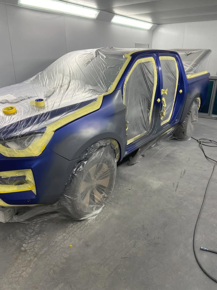Isuzu D-Max masked up in the spray booth with the front wing prepared for blending