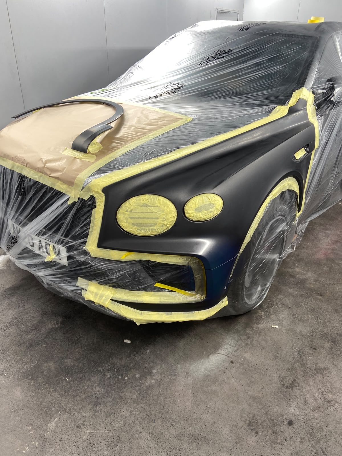 Bentley Bentayga masked up in the spray booth, with the nearside wing and bumper wrapped ready for painting