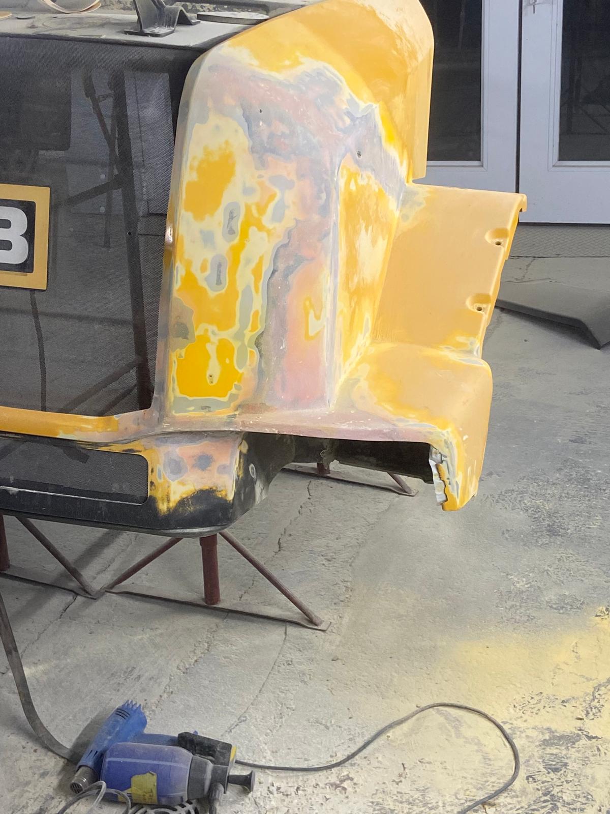 JCB loading shovel bonnet panel sanded back through several layers of old paint, exposing patches of primer and filler underneath